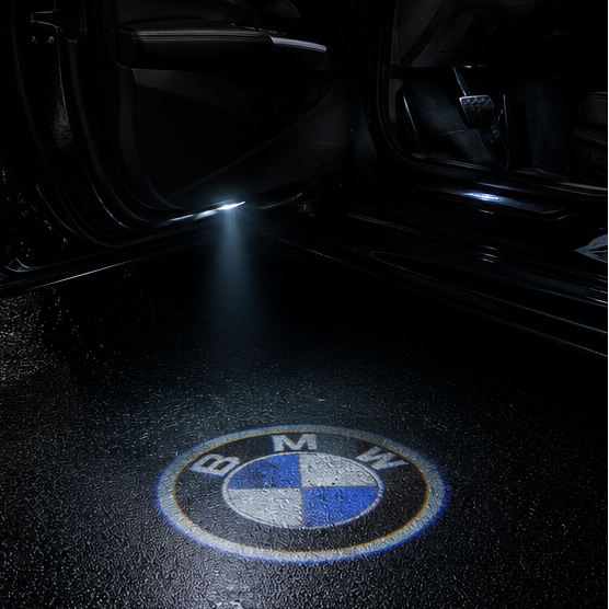 BMW roundel projected onto wet tarmac beside an open car door at night